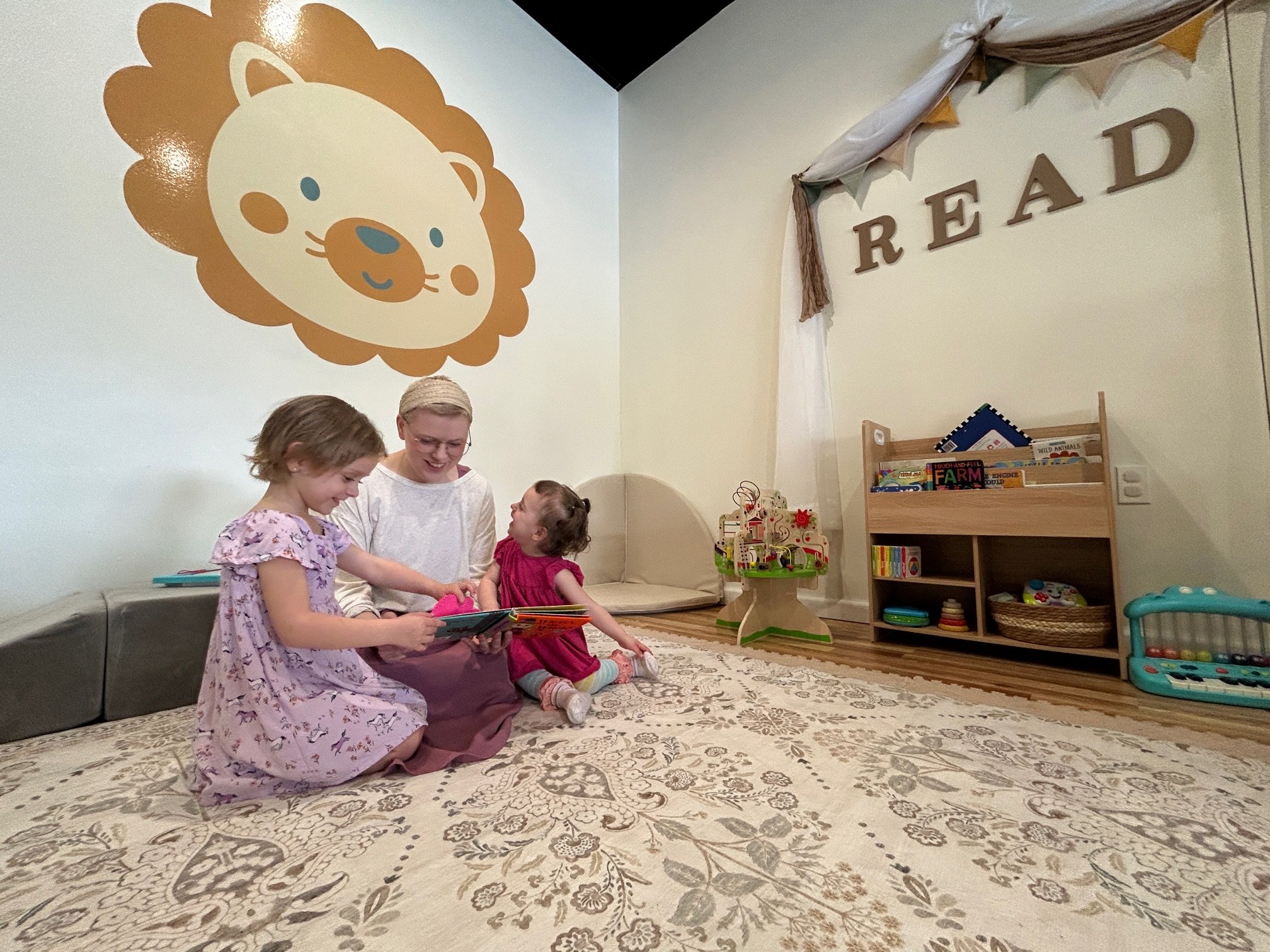 Children and a parent reading together in the Little Lions Den reading nook