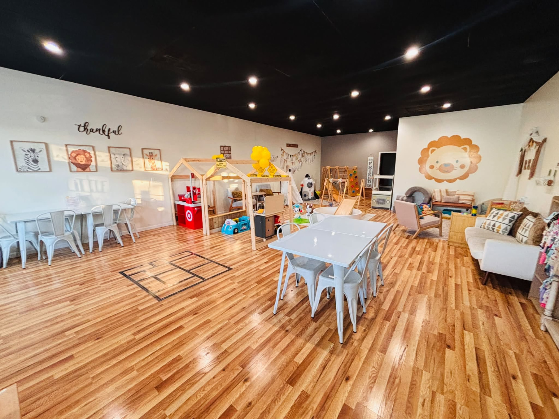The bright Little Lions Den indoor play space, with wooden play stations and cozy seating